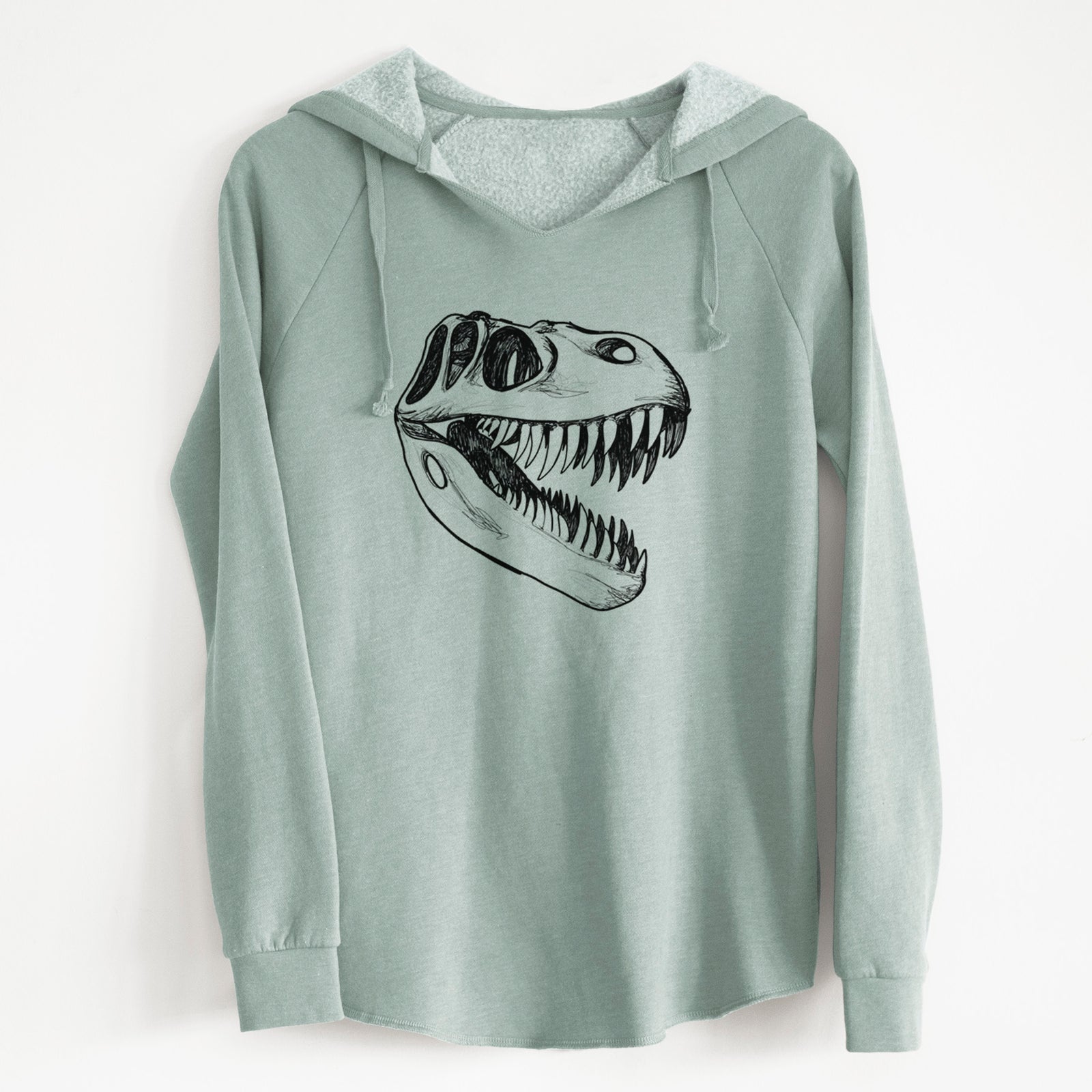 Sage green women's Cali Wave hooded sweatshirt laid flat, printed with a black ink illustration of a Tyrannosaurus rex skull with sharp teeth.
