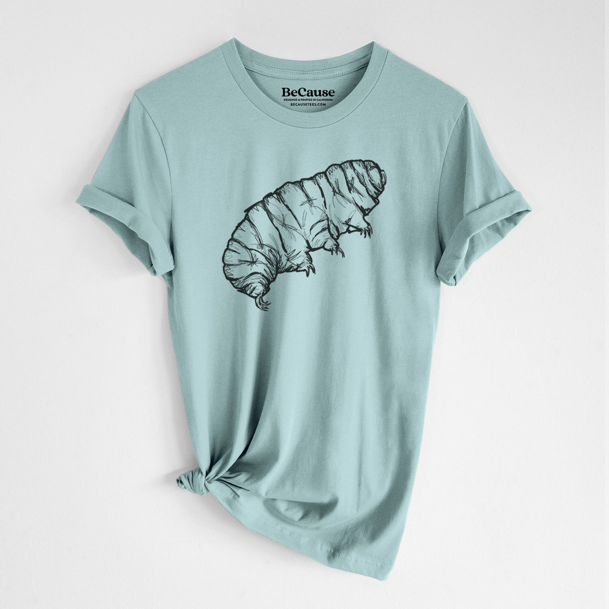 Dusty blue lightweight cotton t-shirt laid flat with the sleeves rolled, printed with a detailed black ink illustration of a tardigrade, or water bear.