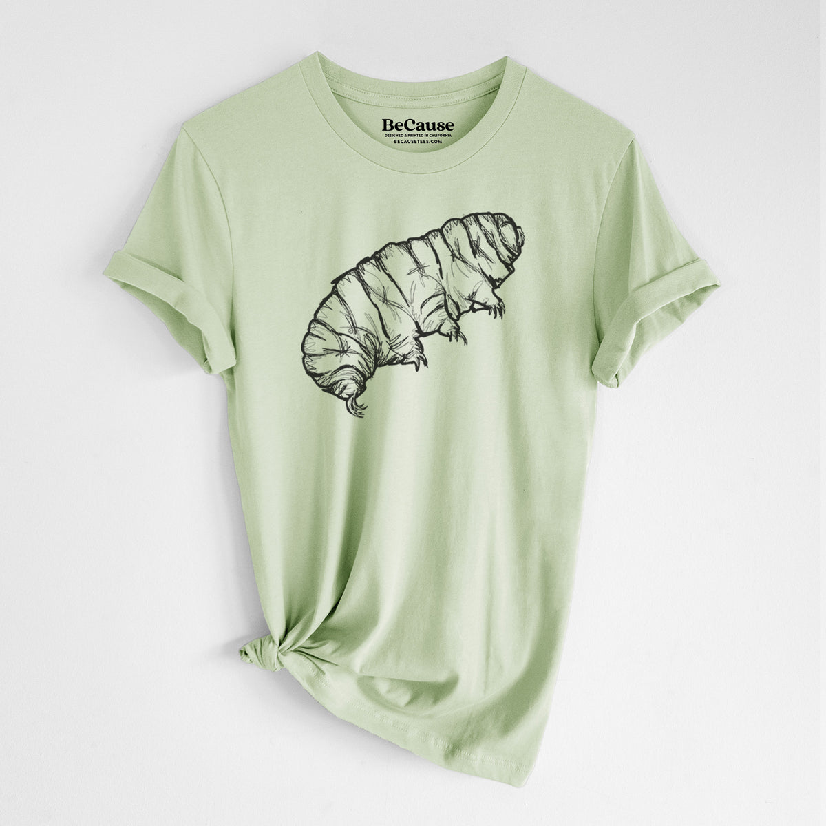Spring green lightweight cotton t-shirt laid flat with the sleeves rolled, printed with a detailed black ink illustration of a tardigrade, or water bear.
