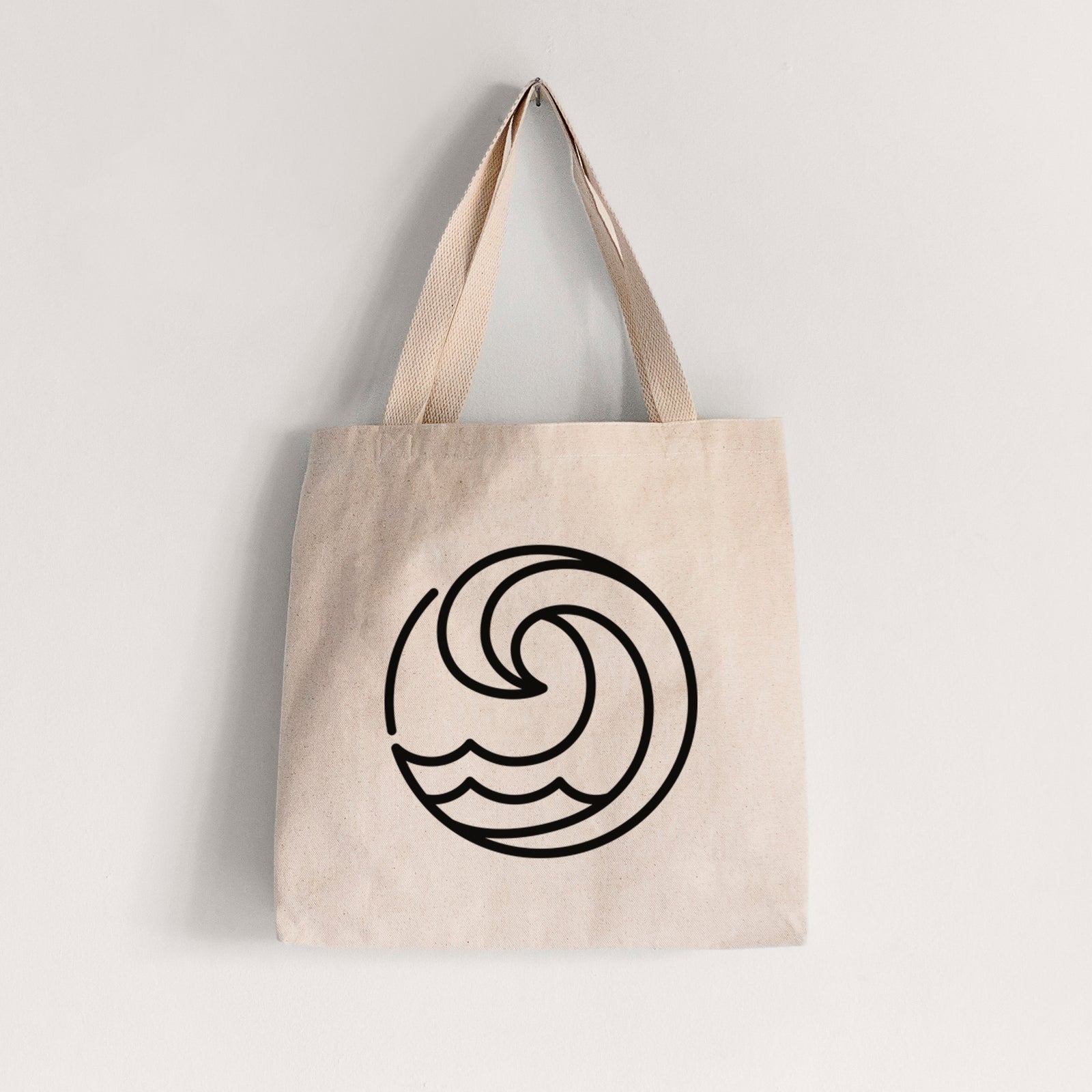 Natural canvas tote bag printed with a bold black line art circle of a curling ocean wave.