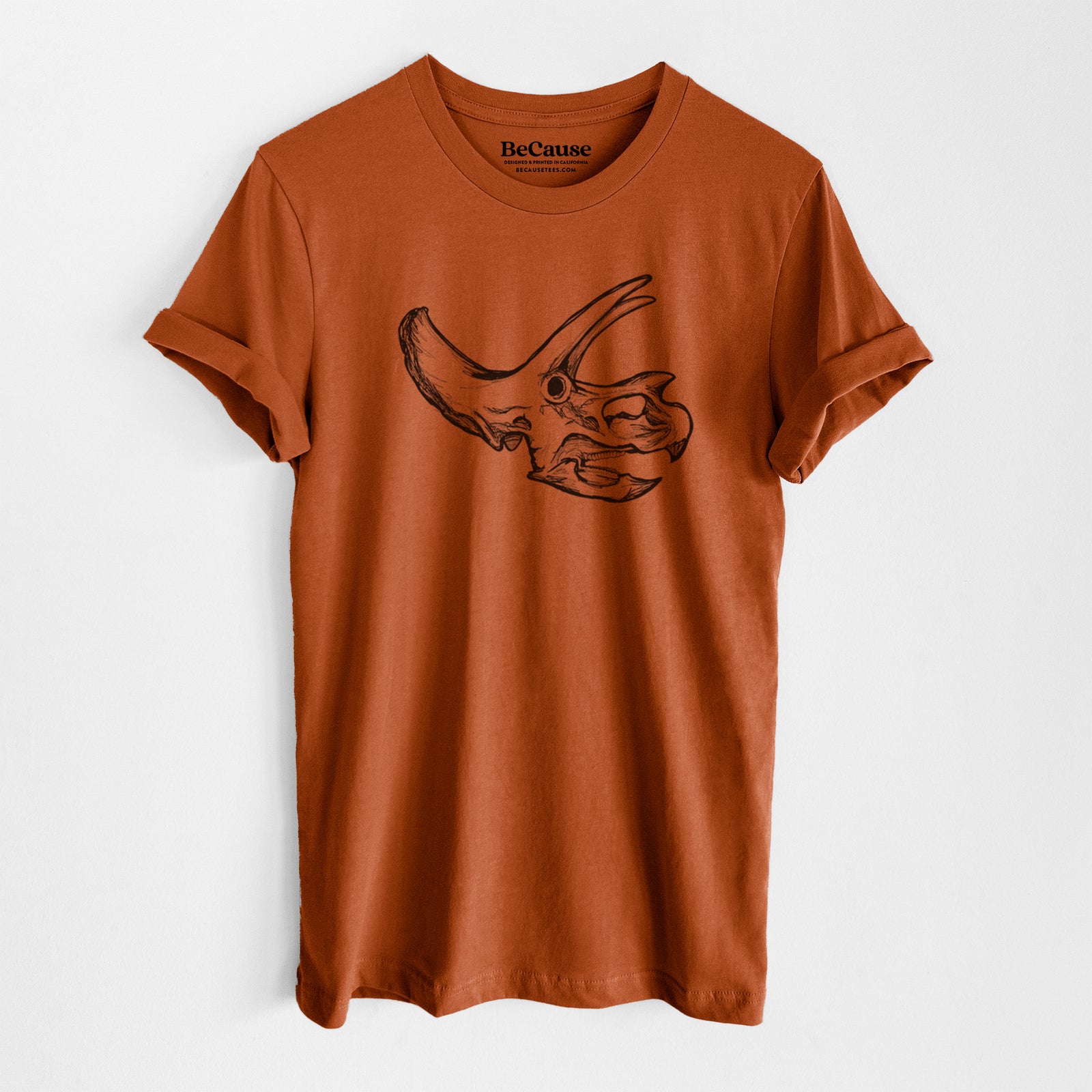Autumn lightweight cotton t-shirt laid flat, printed with a detailed black ink illustration of a Triceratops skull with its horns and frill.