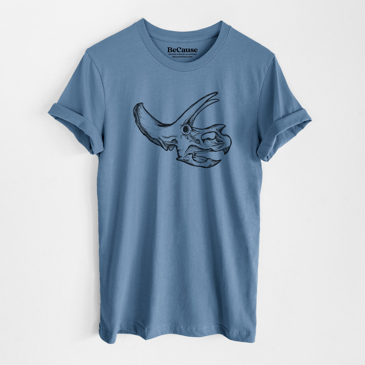 Steel blue lightweight cotton t-shirt laid flat, printed with a detailed black ink illustration of a Triceratops skull with its horns and frill.
