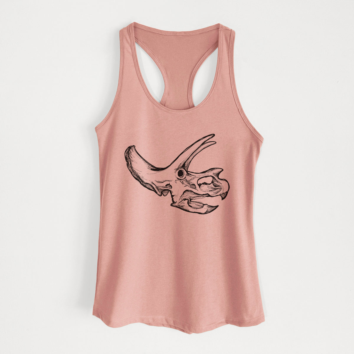 Desert pink women's racerback tank top laid flat, printed with a detailed black ink illustration of a Triceratops skull with its horns and frill.