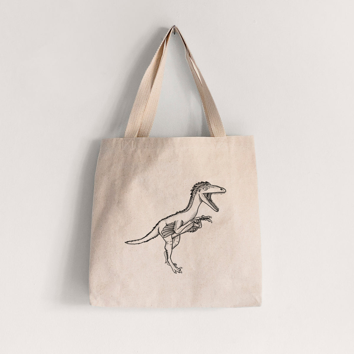 Natural canvas tote bag printed with a black ink illustration of a Troodon dinosaur running.