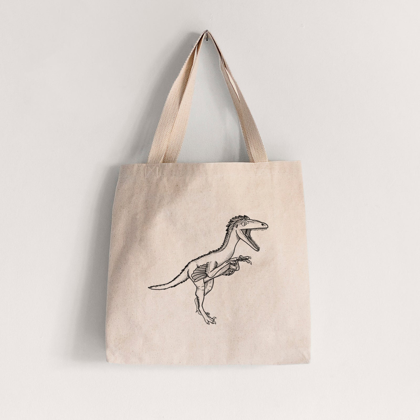 Natural canvas tote bag printed with a black ink illustration of a Troodon dinosaur running.
