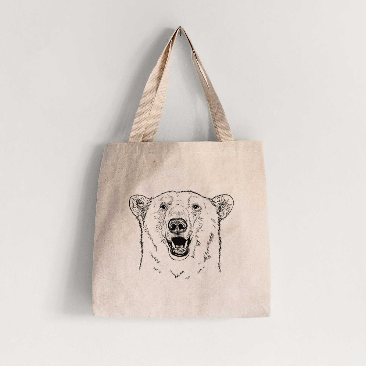 Natural canvas tote bag printed with a black ink portrait of a smiling polar bear's face.