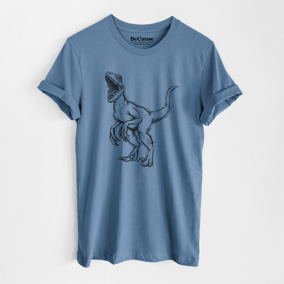 Steel blue lightweight cotton t-shirt laid flat, printed with a black ink illustration of a Velociraptor roaring.
