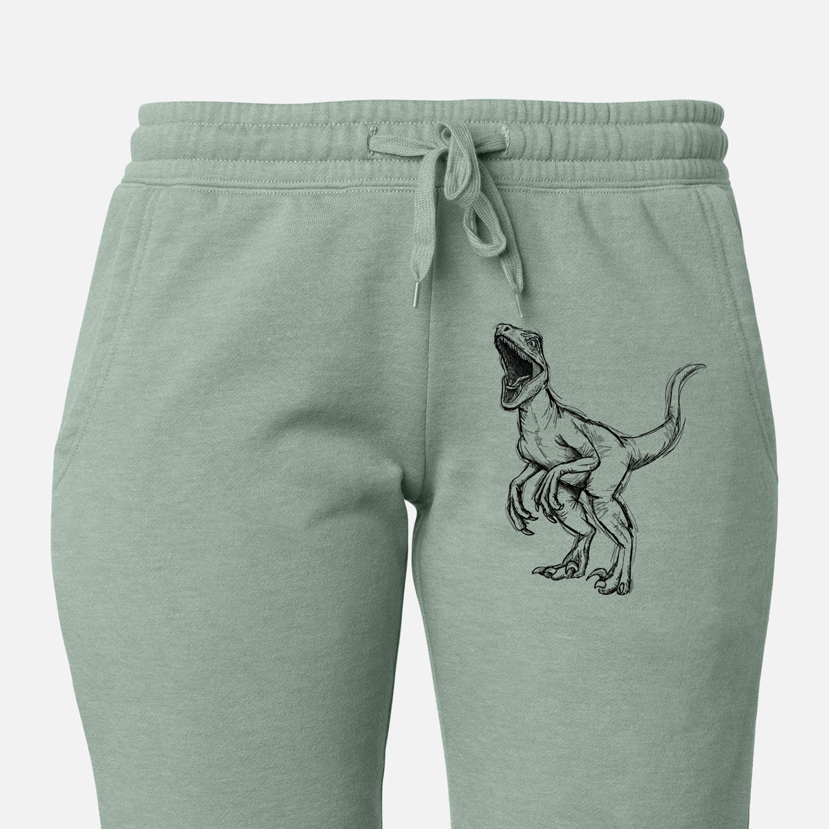 Front of sage green Cali Wave sweatpants, printed with a black ink illustration of a Velociraptor roaring on the leg.