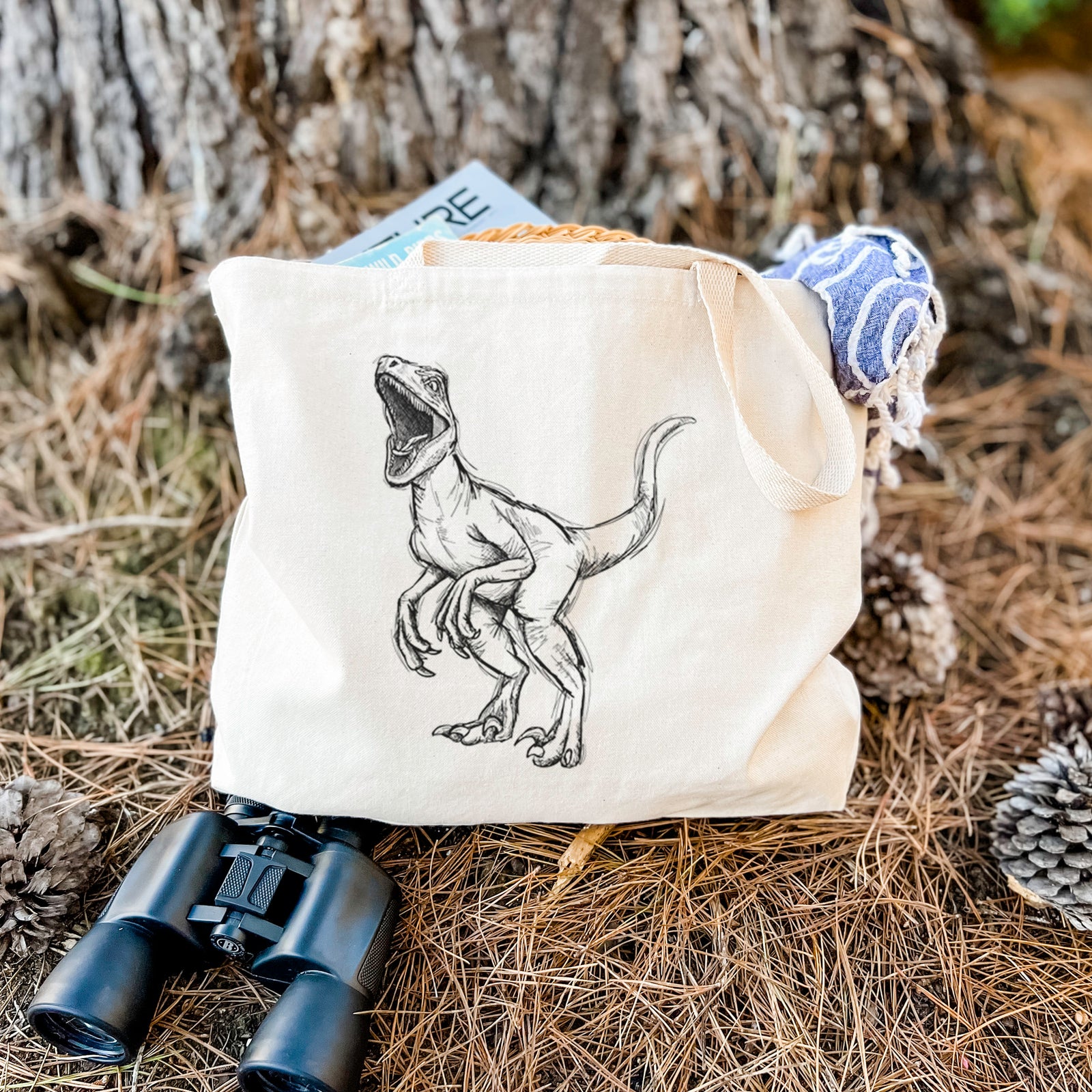 Natural canvas tote bag printed with a black ink illustration of a Velociraptor roaring.