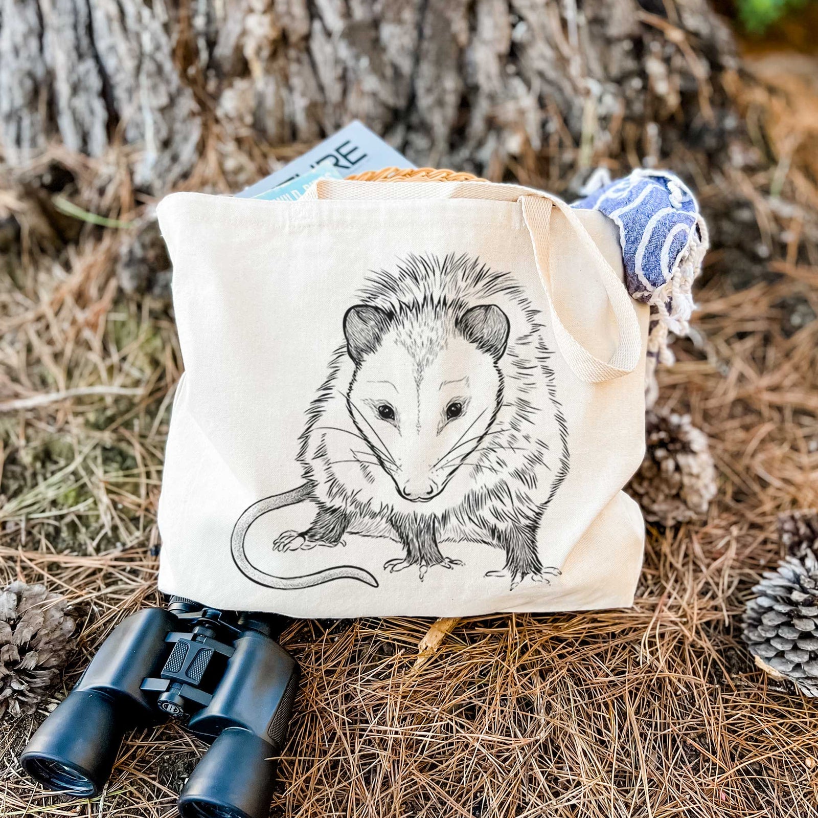 Natural canvas tote bag printed with a detailed black ink illustration of a Virginia opossum standing with its long tail curled.