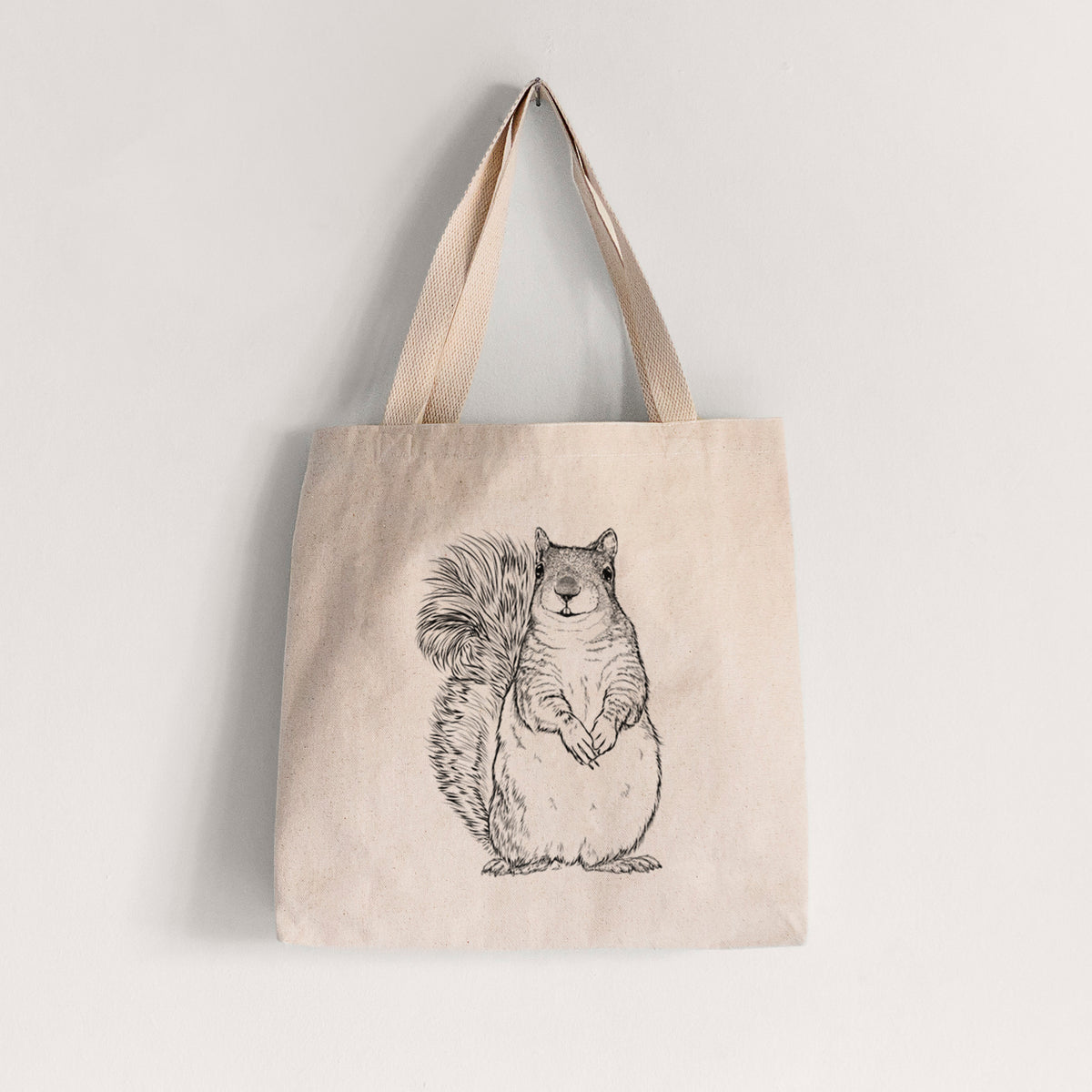 Natural canvas tote bag printed with a detailed black ink illustration of a western grey squirrel sitting upright with a bushy tail.