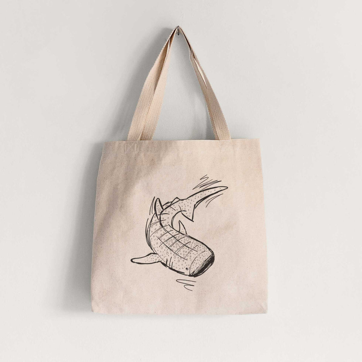 Natural canvas tote bag printed with a black ink illustration of a spotted whale shark swimming.