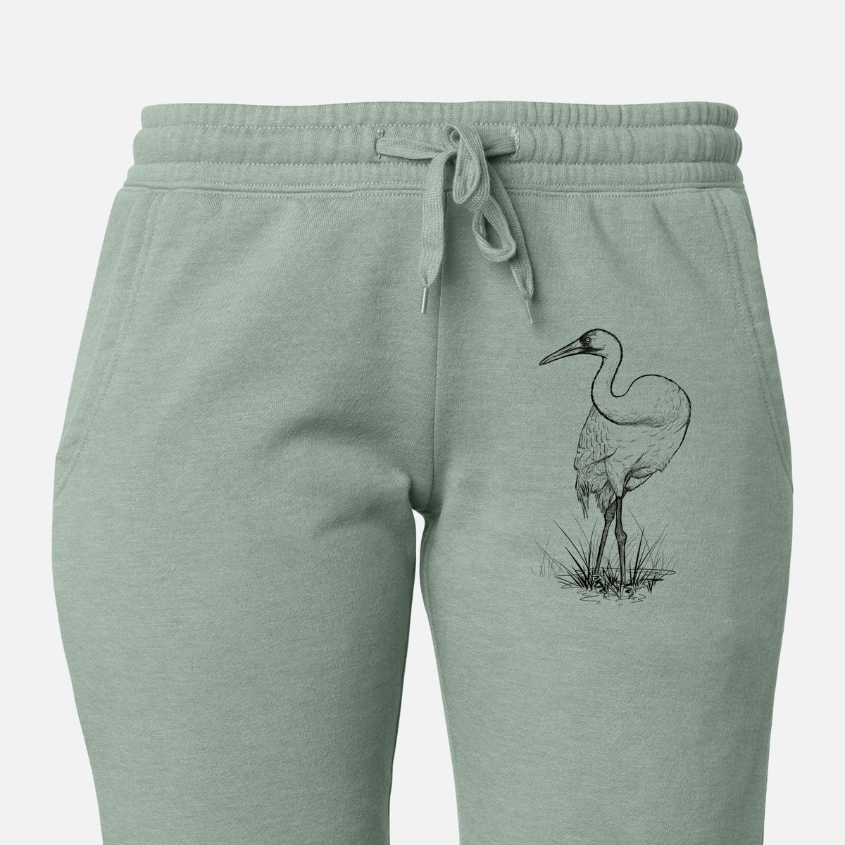 Front of sage green Cali Wave sweatpants, printed with a detailed black ink illustration of a whooping crane standing in grass on the leg.