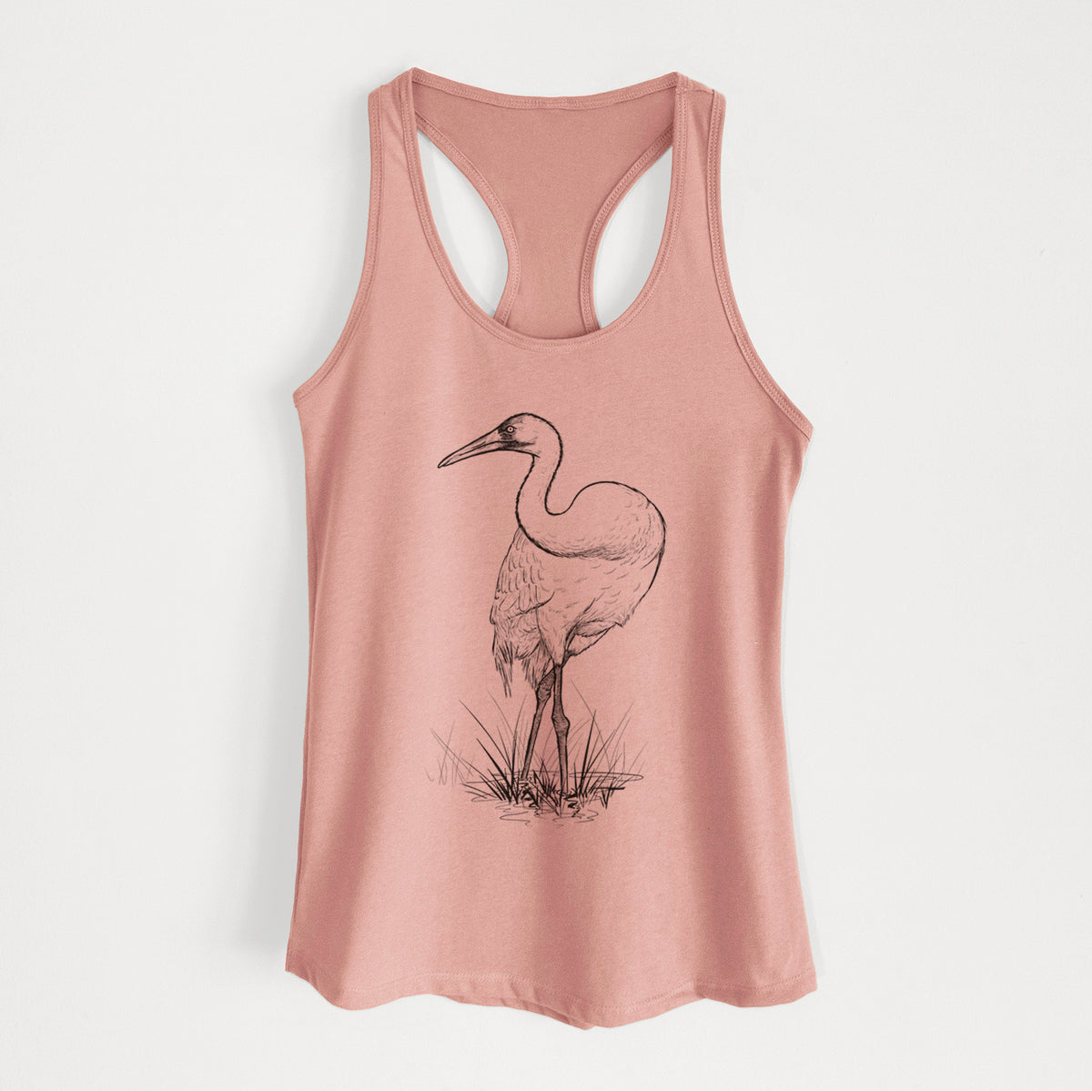 Desert pink women's racerback tank top laid flat, printed with a detailed black ink illustration of a whooping crane standing in grass.