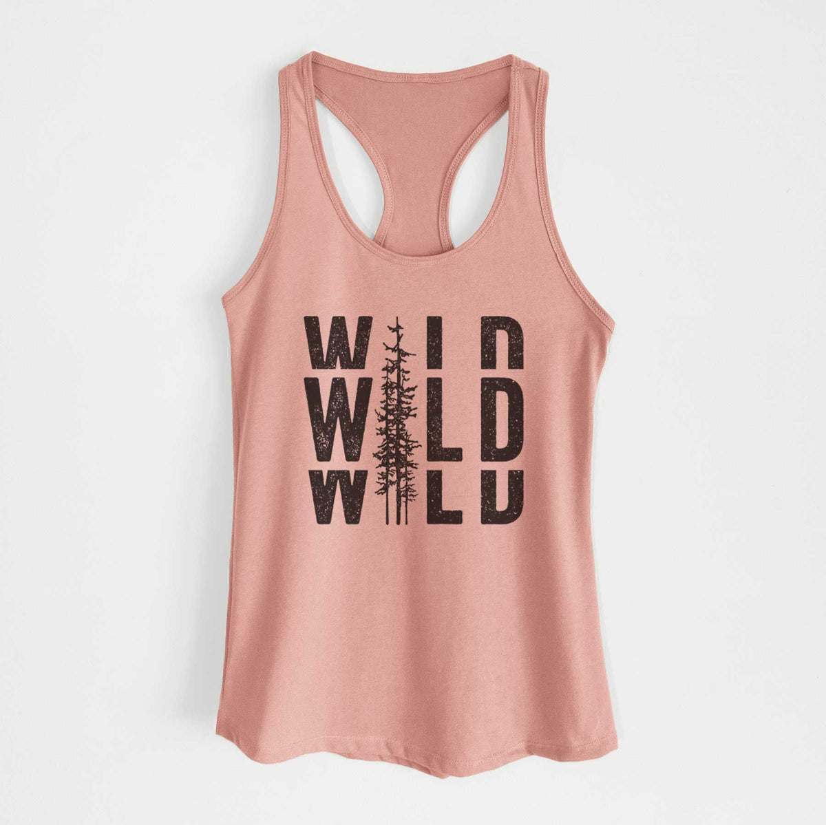 Desert pink women's racerback tank top laid flat, printed with bold black text reading WILD stacked three times, with a tall pine tree forming the letter I.