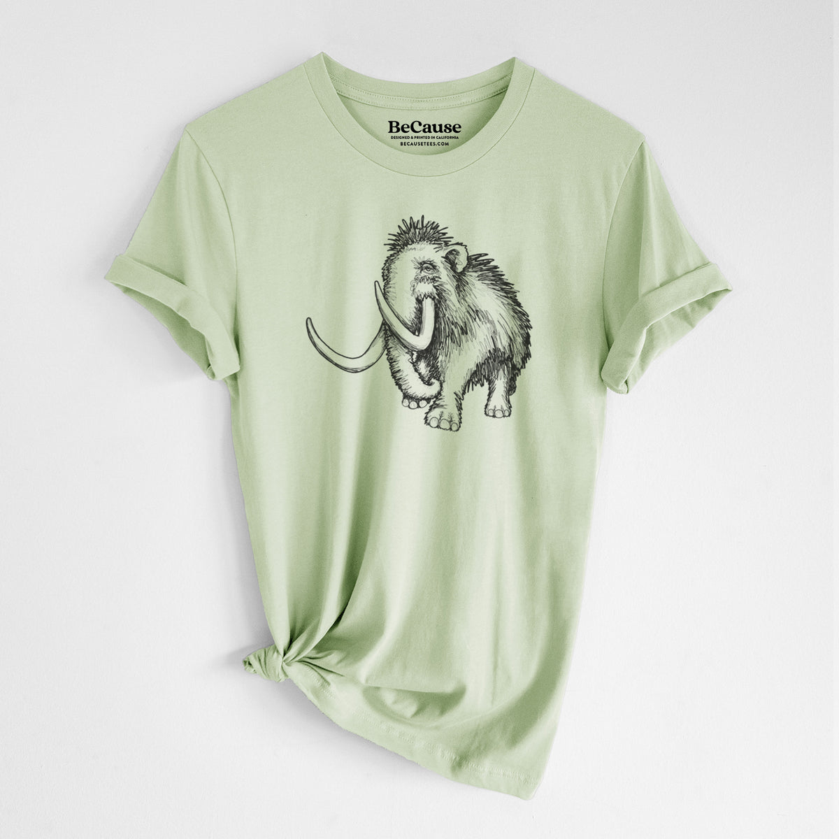 Spring green lightweight cotton t-shirt laid flat with the sleeves rolled, printed with a black ink illustration of a woolly mammoth with long curved tusks.