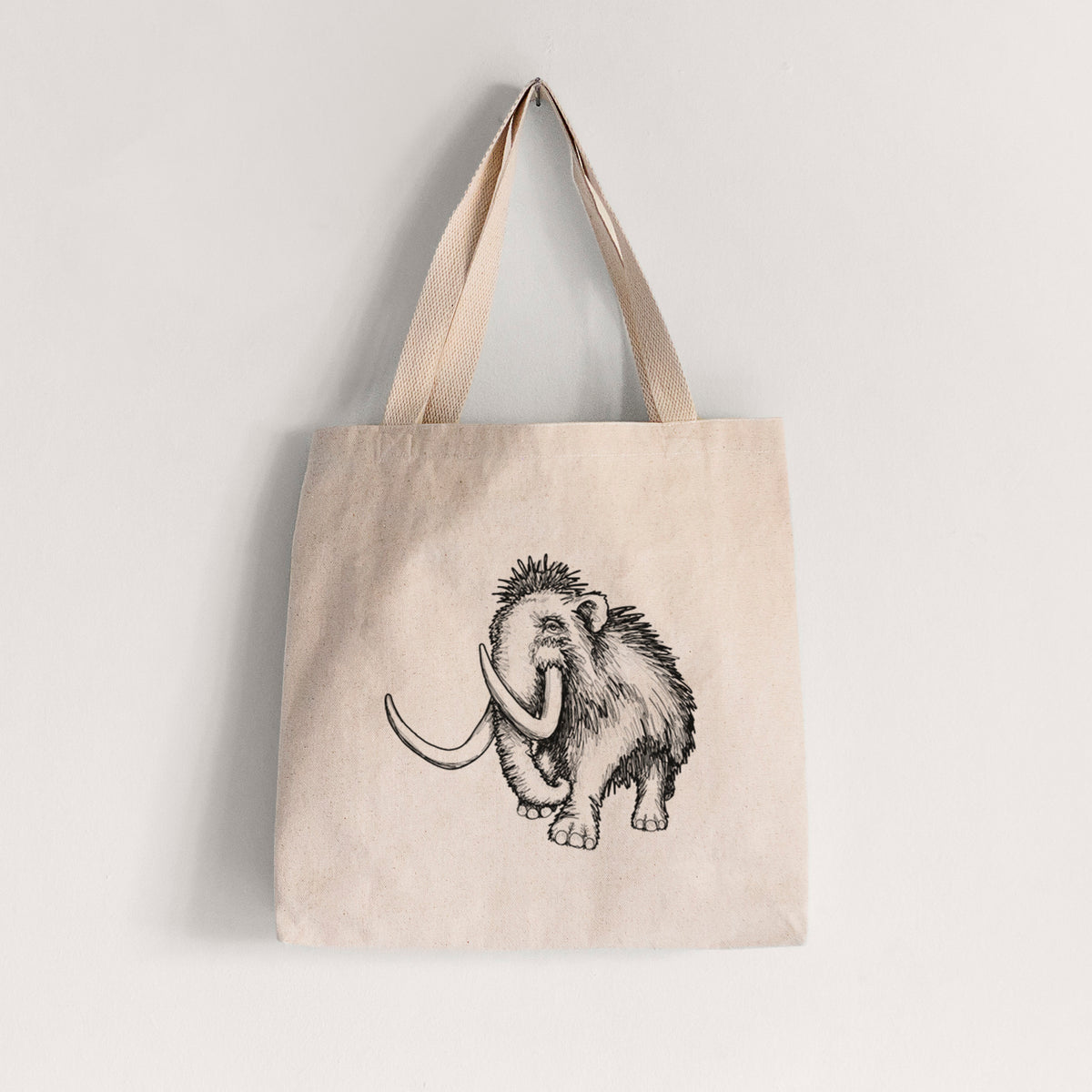 Natural canvas tote bag printed with a black ink illustration of a woolly mammoth with long curved tusks.