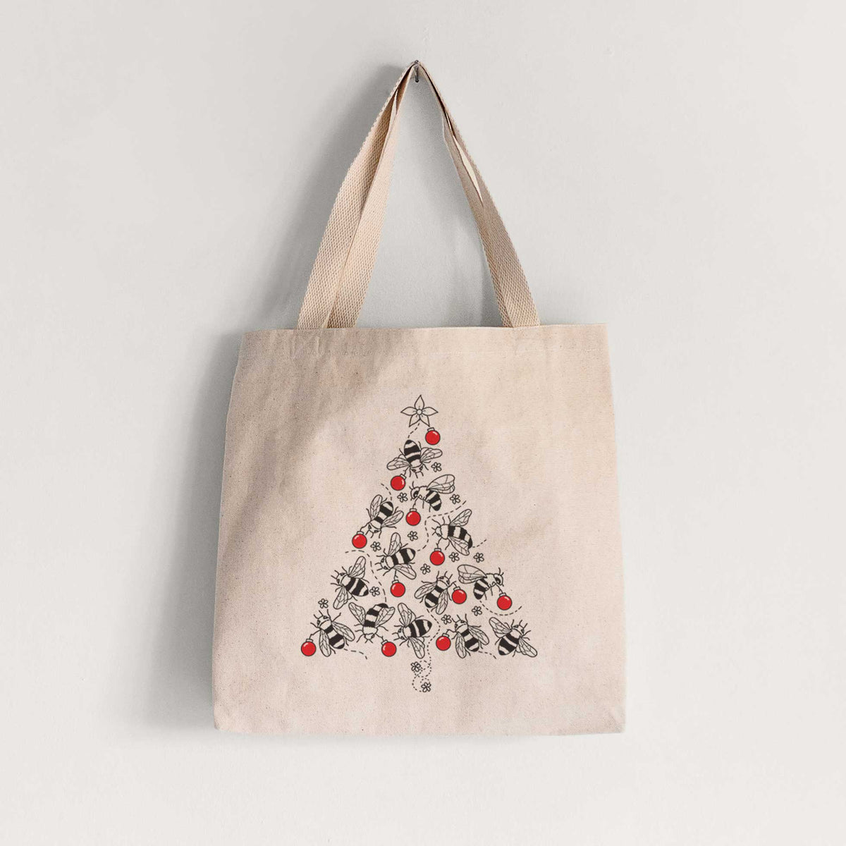 Natural canvas tote bag printed with a Christmas tree made of black ink bees with red ornaments and a star on top.