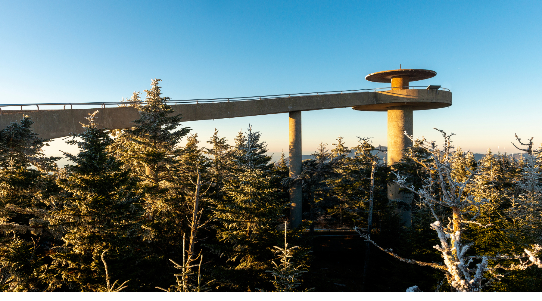 Observation tower at the newly renamed Kuwohi, formerly Clingmans Dome, in the Great Smoky Mountains National Park, surrounded by frosted evergreens under a clear blue sky.