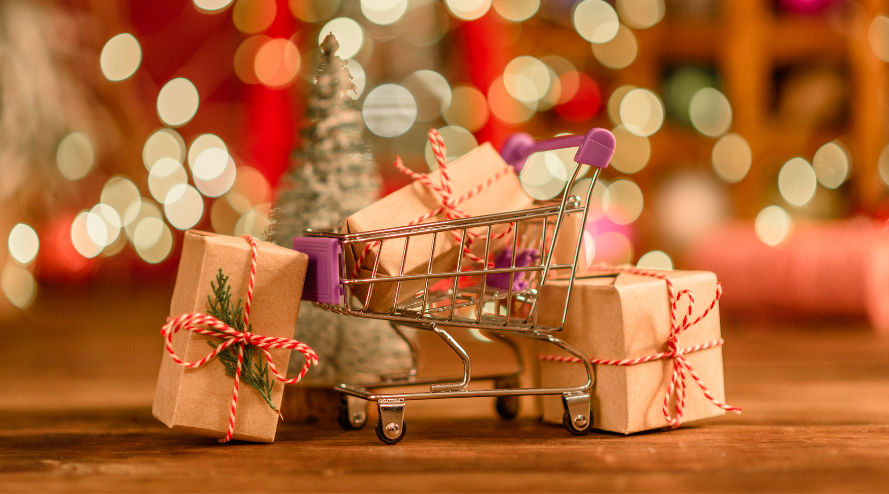 Mini shopping cart filled with wrapped gifts, surrounded by holiday decorations and warm lights, promoting sustainable holiday shopping practices.