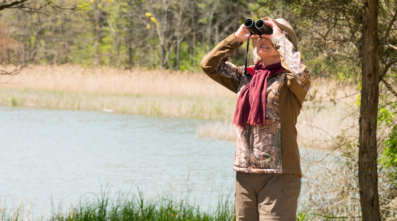 Person bird watching near a lake with binoculars – gift guide for bird watchers