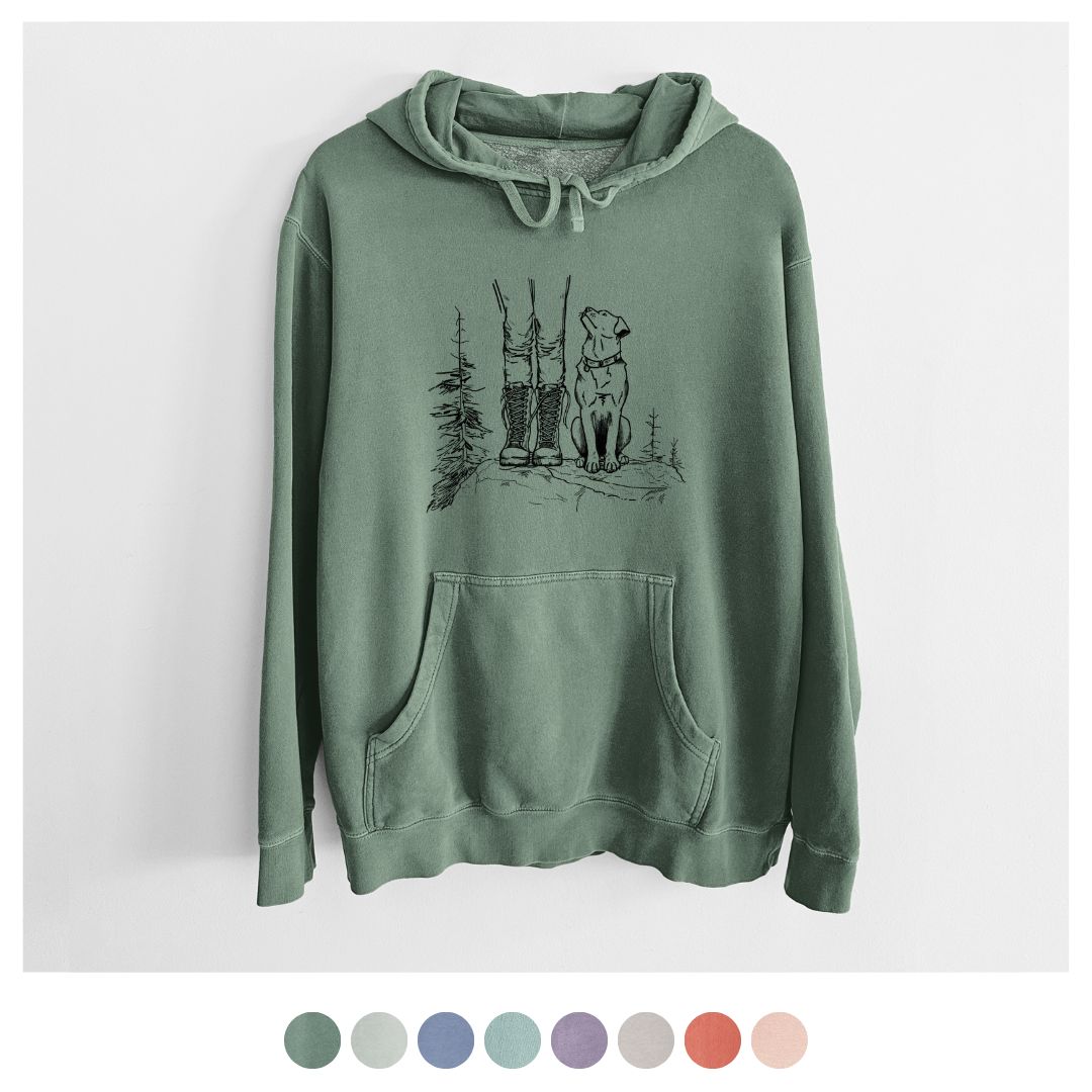 Unisex sage green pigment-dyed hoodie with a hiking boots and dog graphic, featuring color swatches.