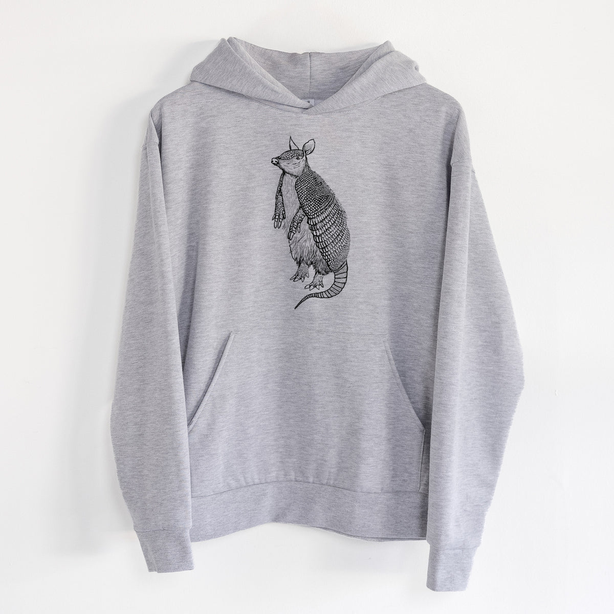 Nine-Banded Armadillo - Dasypus novemcinctus - Statement Midweight Hoodie in Heather Grey, hanging on a white wall, with a front kangaroo pocket and no drawcords.