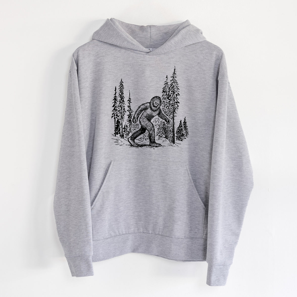 Bigfoot in the Woods - Statement Midweight Hoodie in Heather Grey, hanging on a white wall, with a front kangaroo pocket and no drawcords.