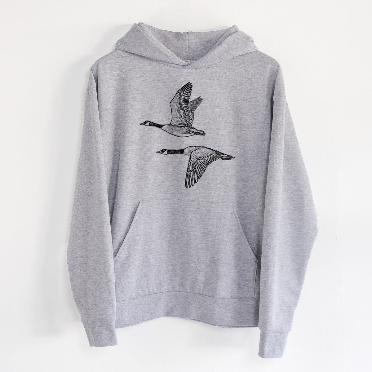 Canada Geese in Flight - Branta canadensis - Statement Midweight Hoodie in Heather Grey, hanging on a white wall, with a front kangaroo pocket and no drawcords.
