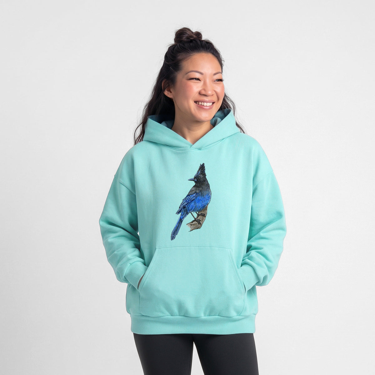 Female model wearing the Vibrant Coastal Steller's Jay - Cyanocitta stelleri - Statement Midweight Hoodie.