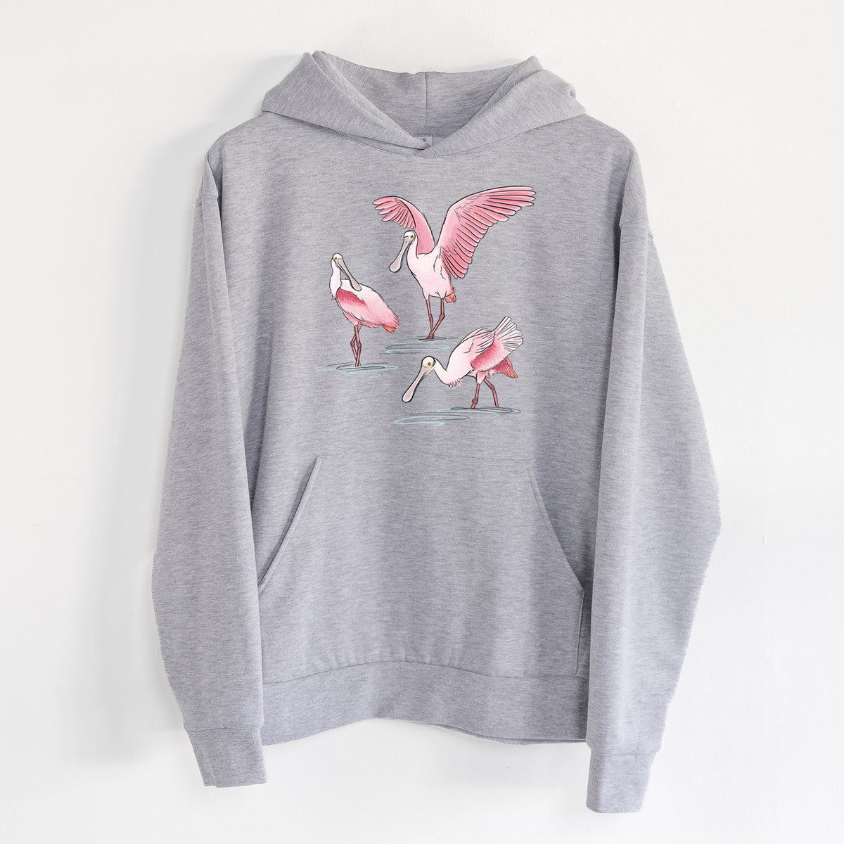 Roseate Spoonbill Trio - Platalea ajaja - Statement Midweight Hoodie in Heather Grey, hanging on a white wall, with a front kangaroo pocket and no drawcords.