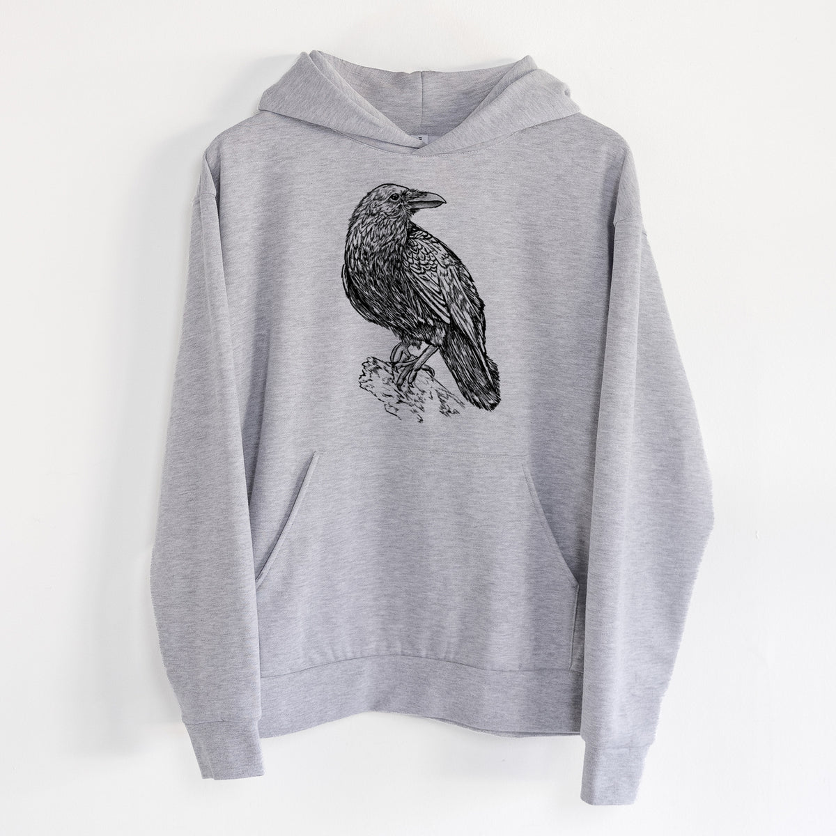 Corvus corax - Common Raven - Statement Midweight Hoodie in Heather Grey, hanging on a white wall, with a front kangaroo pocket and no drawcords.