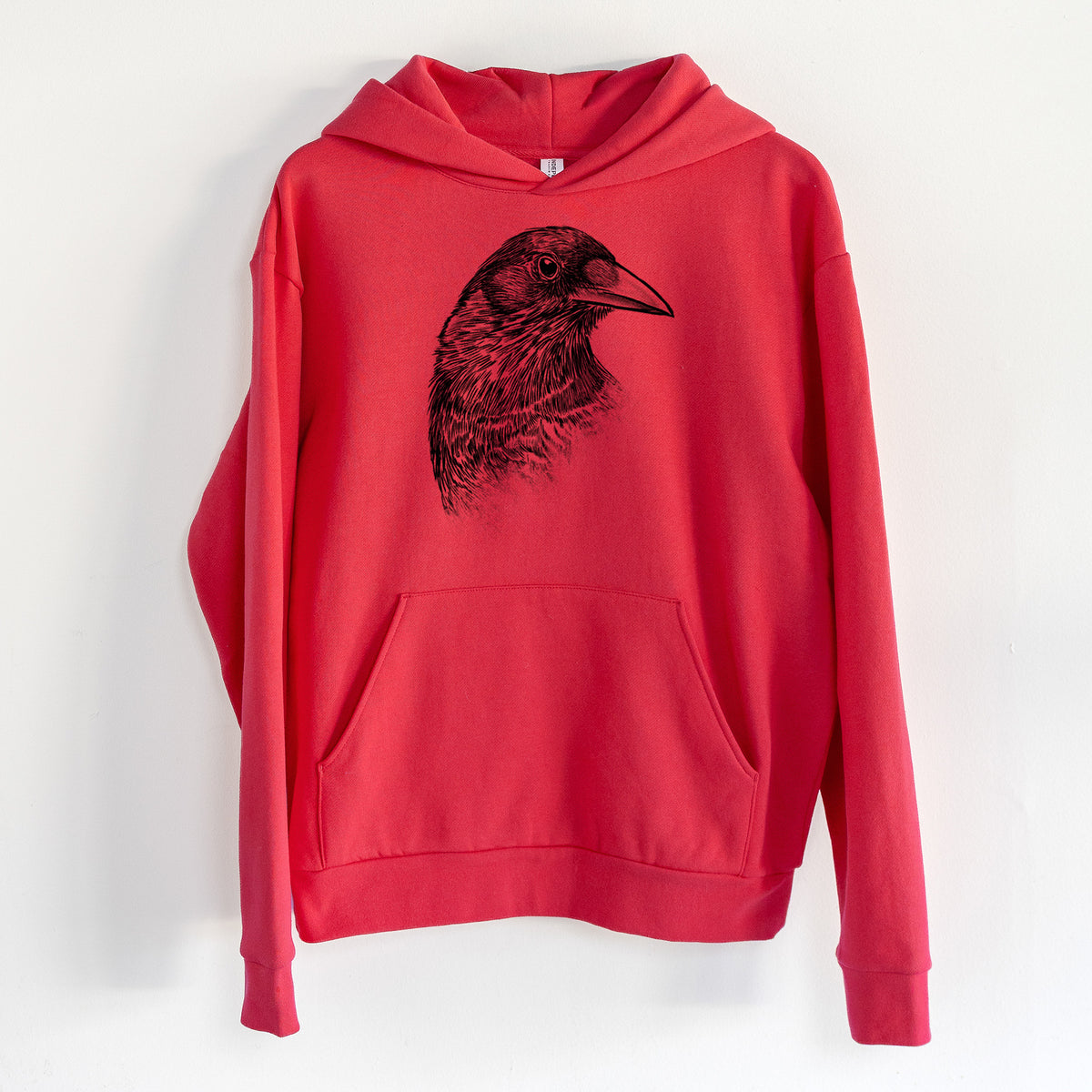 American Crow Bust - Corvus brachyrhynchos - Statement Midweight Hoodie in Cherry Red, hanging on a white wall, with a front kangaroo pocket and no drawcords.