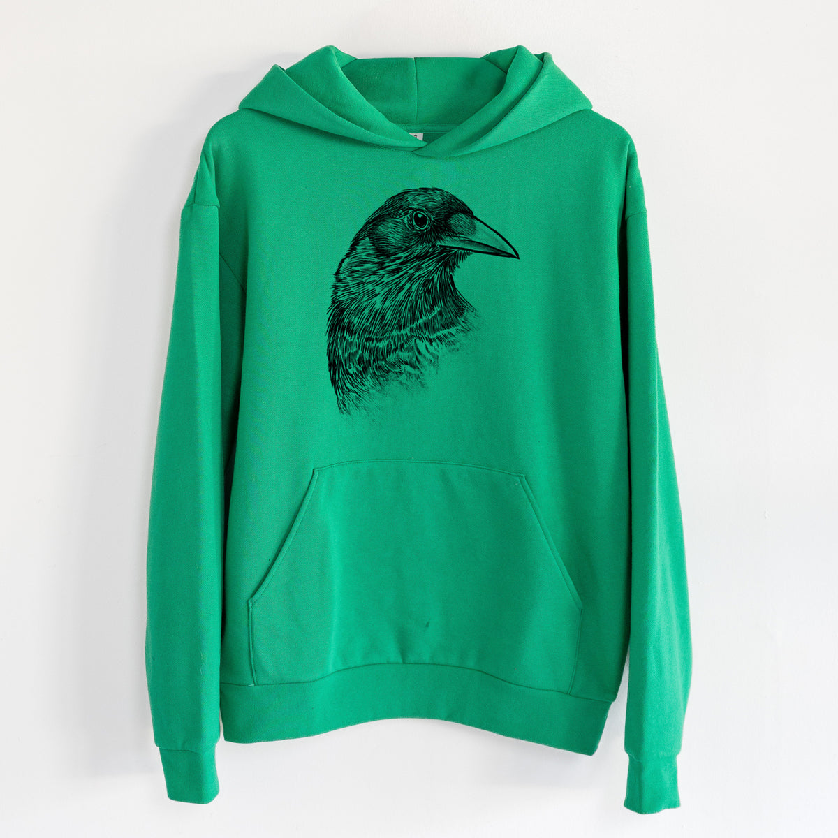 American Crow Bust - Corvus brachyrhynchos - Statement Midweight Hoodie in Kelly Green, hanging on a white wall, with a front kangaroo pocket and no drawcords.