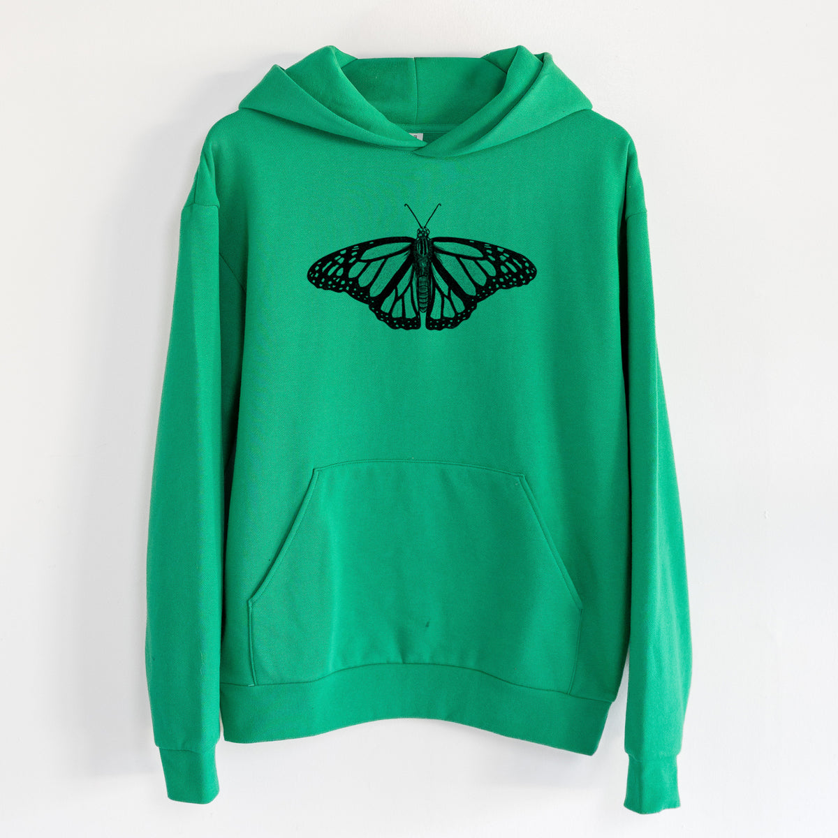Danaus plexippus - Monarch Butterfly - Statement Midweight Hoodie in Kelly Green, hanging on a white wall, with a front kangaroo pocket and no drawcords.