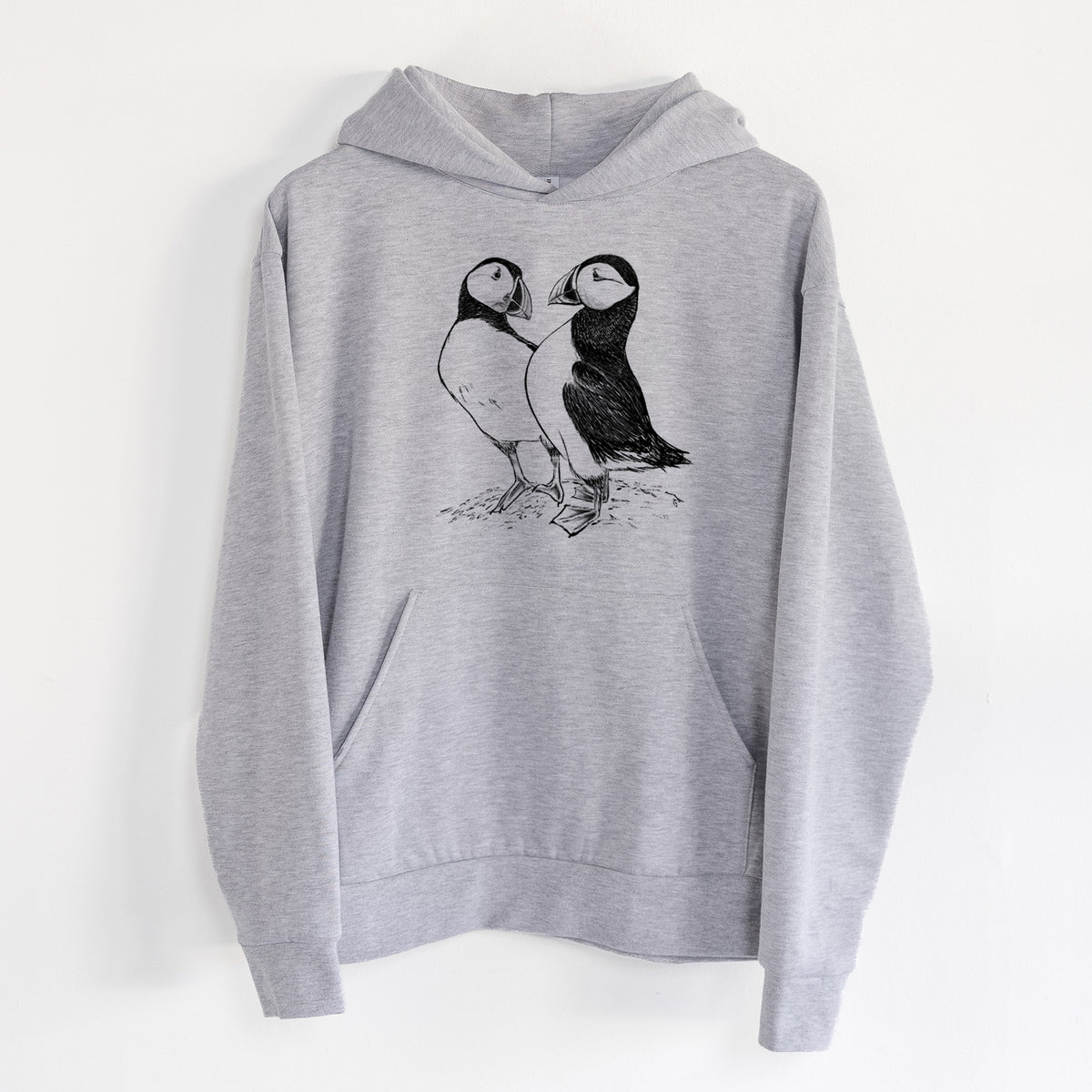 Atlantic Puffins Pair - Fratercula arctica - Statement Midweight Hoodie in Heather Grey, hanging on a white wall, with a front kangaroo pocket and no drawcords.