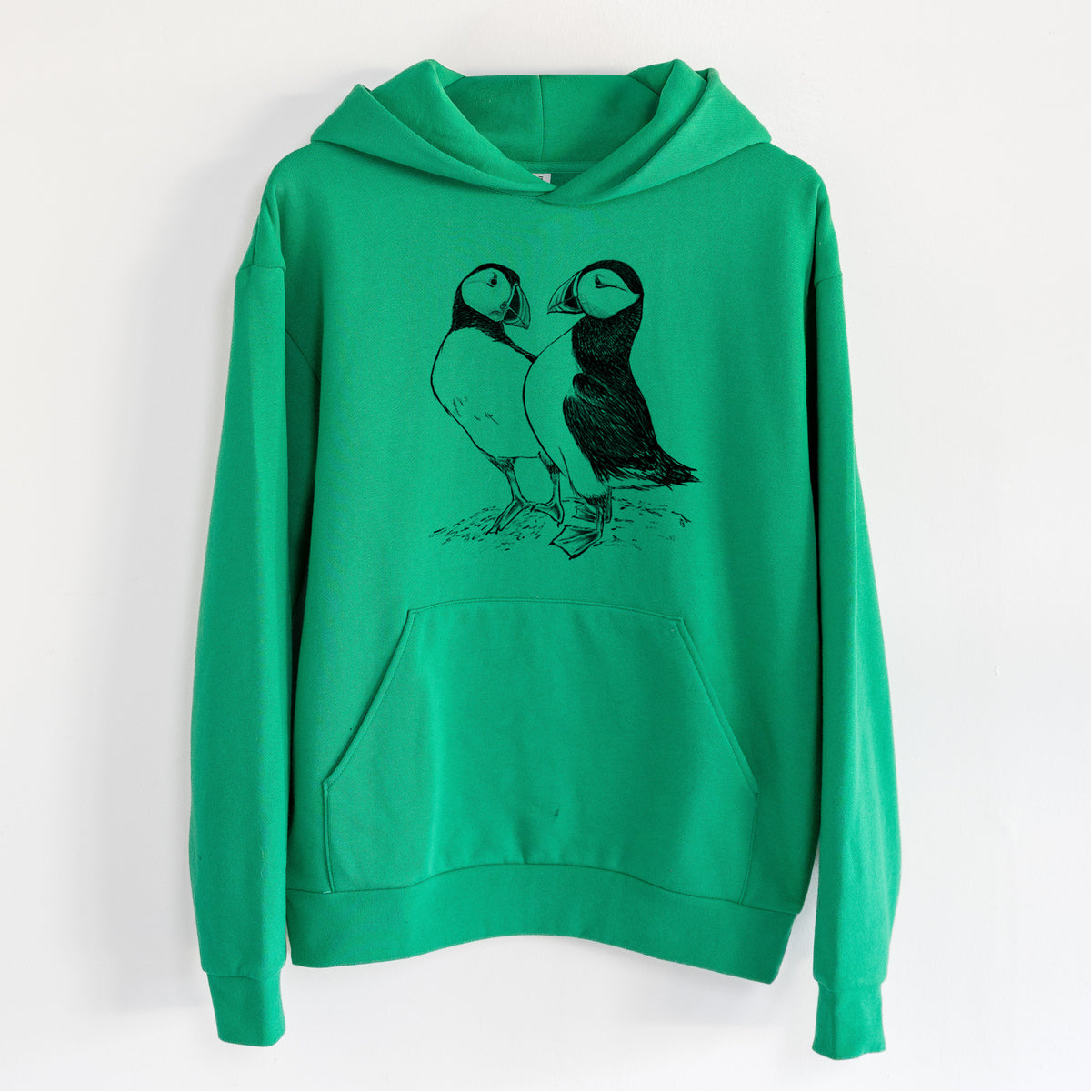 Atlantic Puffins Pair - Fratercula arctica - Statement Midweight Hoodie in Kelly Green, hanging on a white wall, with a front kangaroo pocket and no drawcords.