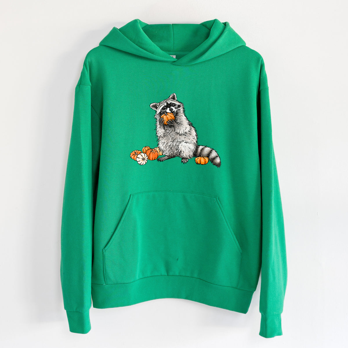 Raccoon Pumpkin Bandit - Statement Midweight Hoodie in Kelly Green, hanging on a white wall, with a front kangaroo pocket and no drawcords.